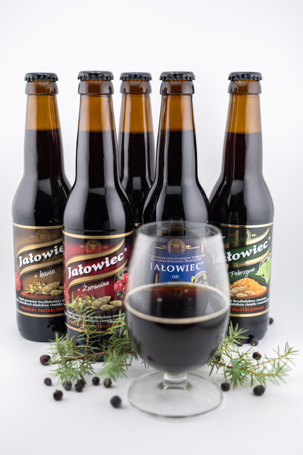 Propozycja podania jałowca z kawą. W tle butelki dostępnych smaków napoju jałowiec.