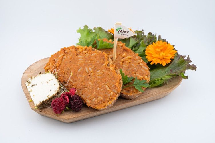 Propozycja podania paprykarzu z pstrąga wędzonego. Dwie kromki chleba posmarowane pastą z ryby na drewnianej desce.